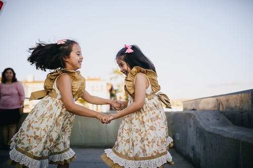 2个穿着白色花裙子的女孩在大街上跳舞 · 免费素材图片