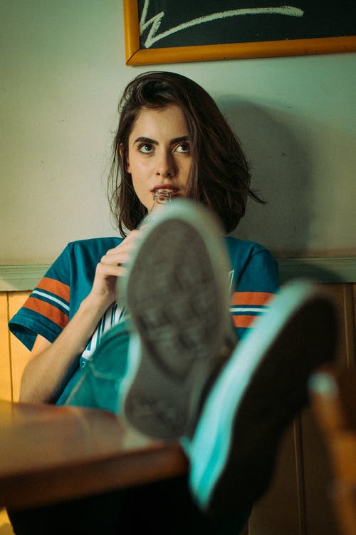 女人坐在棕色的椅子上 · 免费素材图片