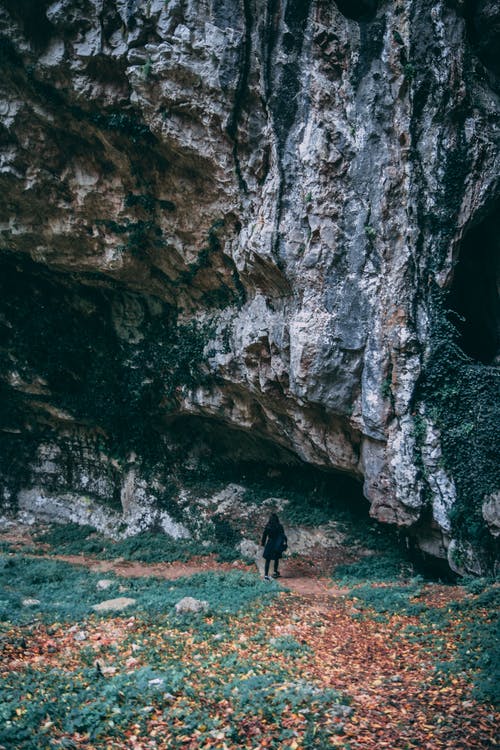 穿黑大衣的女人站在灰色的山附近 · 免费素材图片
