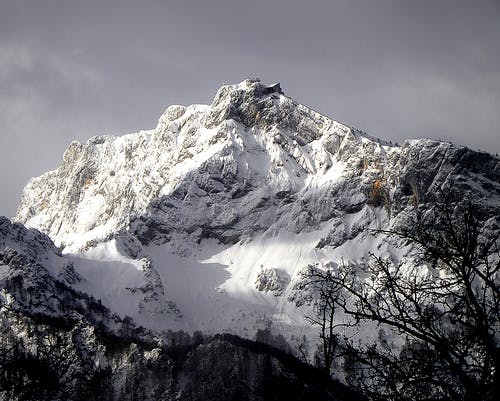 在树附近的雪覆盖的山峭壁风景照片 · 免费素材图片