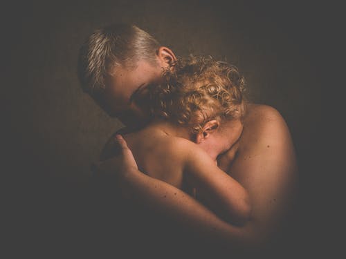 裸照的人抱着卷发的孩子的照片 · 免费素材图片