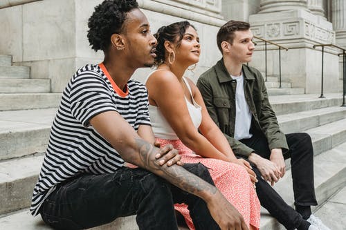 坐在旁边穿着粉红色无袖连衣裙的女人的黑色和白色条纹polo衫的男人 · 免费素材图片