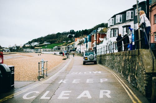 白天灰色混凝土墙和房屋附近的银色停车场 · 免费素材图片
