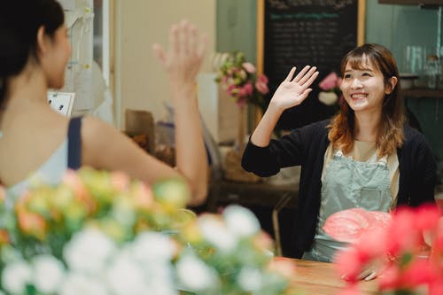 快乐的女性花店，挥舞着的手在店里 · 免费素材图片