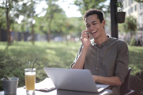 开朗的黑人男性企业家谈夏季咖啡馆的智能手机 · 免费素材图片