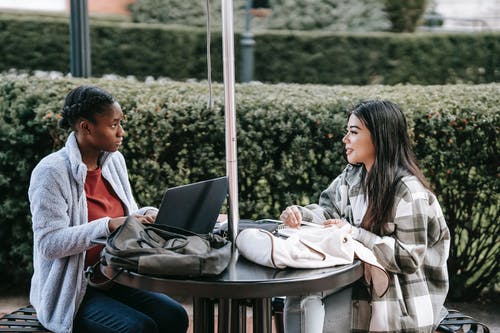 男人和女人坐在长椅上，使用便携式计算机 · 免费素材图片