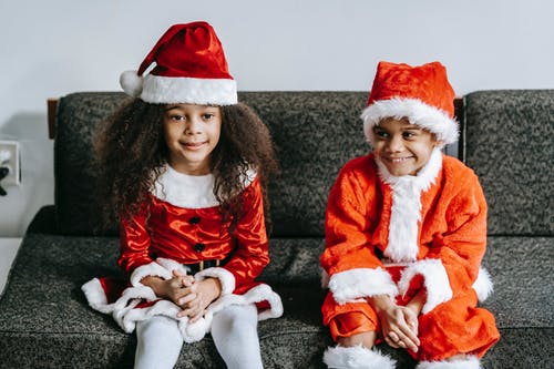 红色和白色的圣诞老人服装，坐在棕色沙发上的女孩 · 免费素材图片