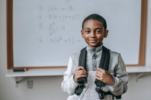微笑在白板附近的黑人男小学生在教室里 · 免费素材图片