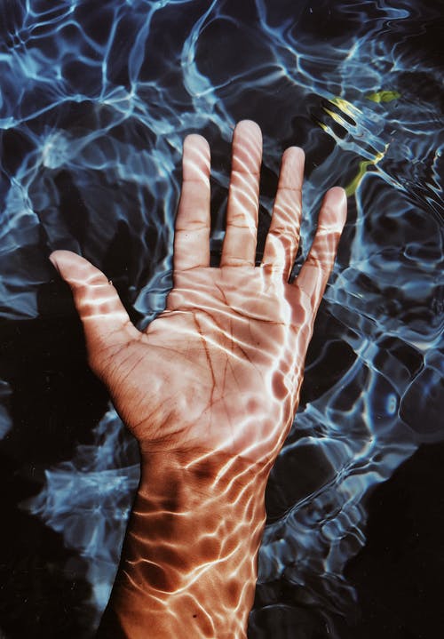 淹没在水中的人的手的照片 · 免费素材图片