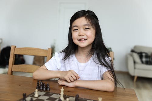 坐在棋盘旁的快乐可爱的亚洲女孩 · 免费素材图片