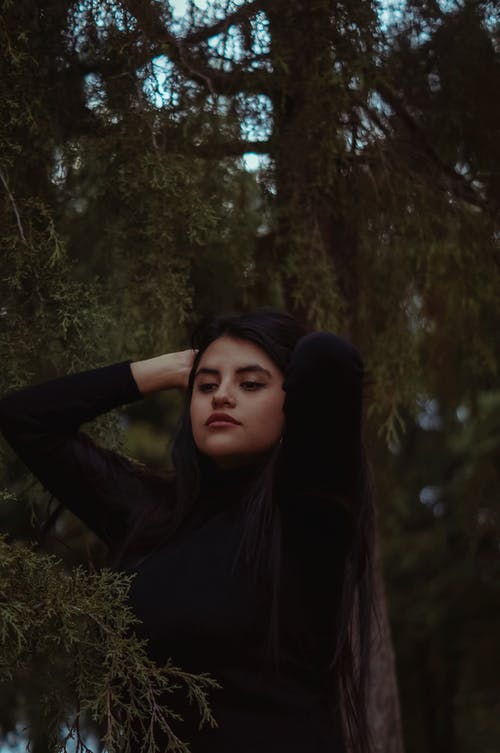 固定她的头发在松树附近的女人 · 免费素材图片