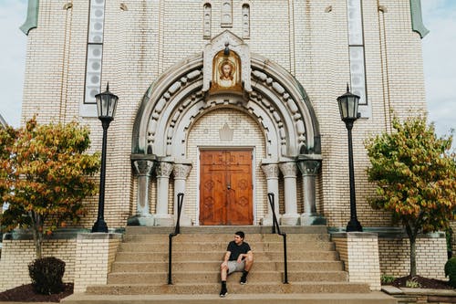 坐在教堂前的男人穿黑色圆领衬衫 · 免费素材图片
