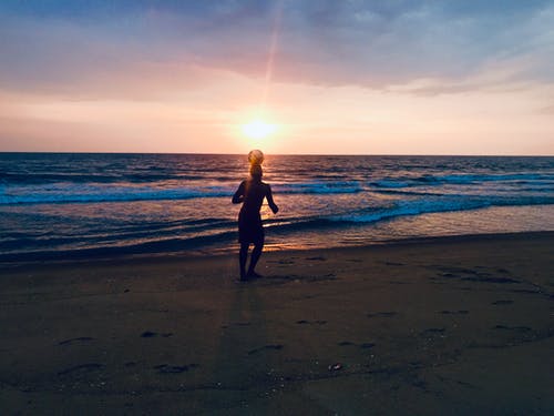 在海边玩球的人的身影 · 免费素材图片