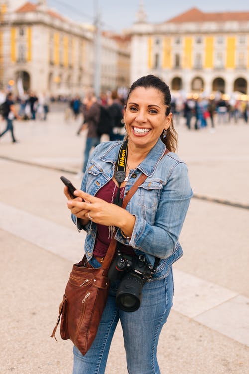 微笑的女士拿着智能手机选择性聚焦摄影 · 免费素材图片