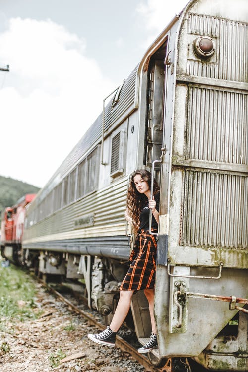 站在一列老火车的门口上的女人穿的衣服 · 免费素材图片