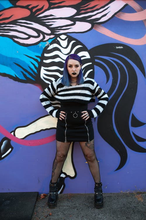 黑色和白色的条纹的长袖衬衫和黑色的裙子站在蓝色墙边的女人 · 免费素材图片