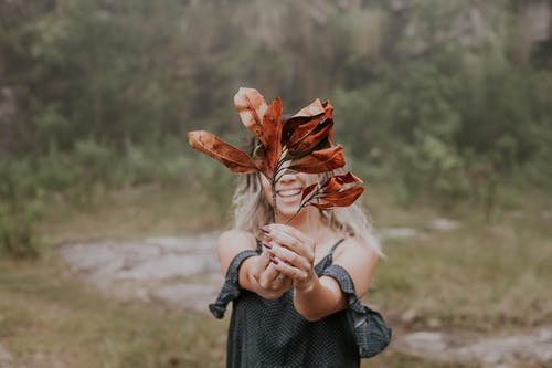 女人抱着干树叶的照片 · 免费素材图片