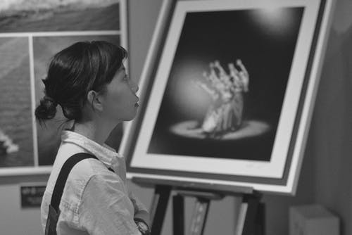 女人站在绘画旁边的灰度照片 · 免费素材图片
