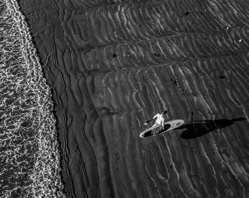 人站在冲浪板上的灰度照片 · 免费素材图片