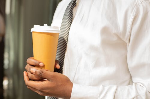 一个穿着正装衬衫拿着咖啡杯的人 · 免费素材图片