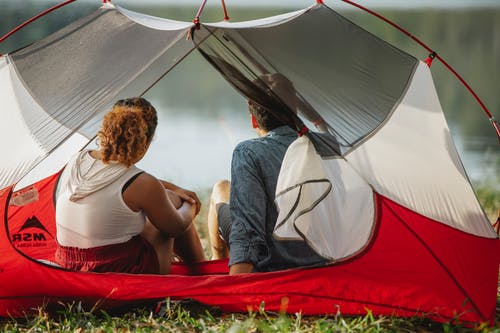白色背心坐在红色和白色帐篷上的女人 · 免费素材图片