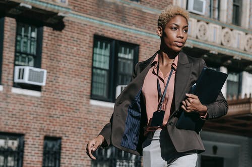 黑色外套站在棕色砖建筑附近的女人 · 免费素材图片