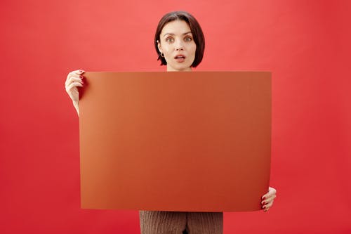 女人拿棕色纸与红色背景 · 免费素材图片