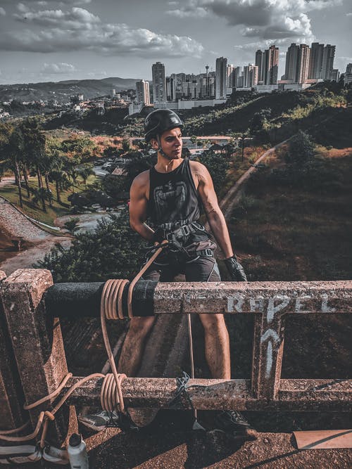 黑色背心和黑色裤子站在棕色金属栏杆上的女人 · 免费素材图片