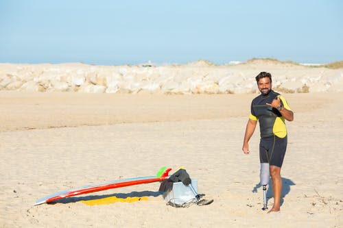积极的民族截肢男子在海滩上显示沙加标志 · 免费素材图片