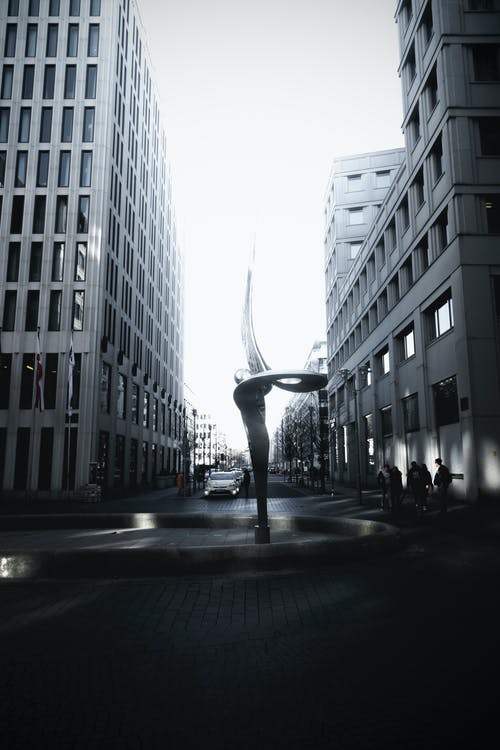 两座高层建筑之间的螺旋形喷泉雕像 · 免费素材图片