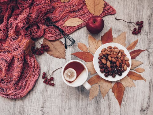 苹果在白色陶瓷杯茶和杏仁和坚果板棕色木制的桌子上 · 免费素材图片