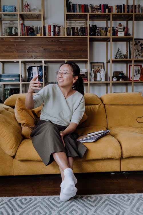 坐在长沙发上的灰色长袖衬衫的女人 · 免费素材图片