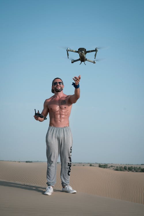 男子手持无人机远程站在灰色的混凝土路面上 · 免费素材图片