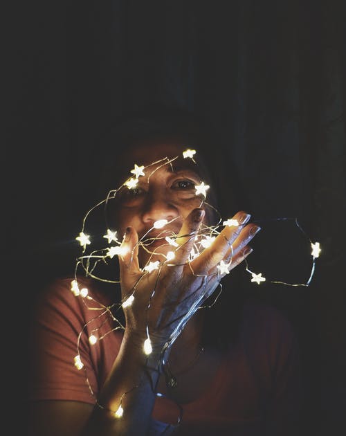 一个女人抱着串灯的特写照片 · 免费素材图片