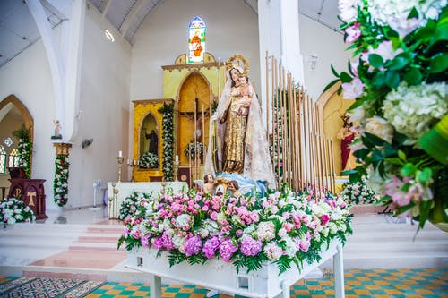 母亲和儿童的雕像包围着靠近教堂祭坛的花朵 · 免费素材图片