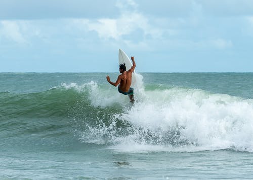 男子骑在水面上的冲浪板 · 免费素材图片