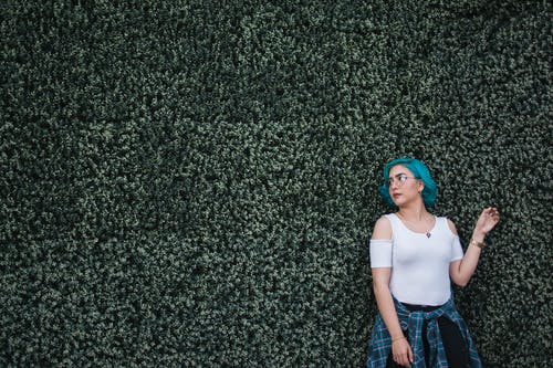 白顶站在绿叶对冲墙前的女人 · 免费素材图片