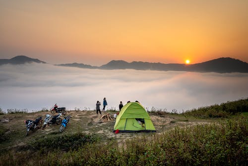 黄金时段，人们站在露营帐篷附近俯瞰云海 · 免费素材图片