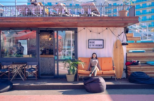 女人坐在橙色的沙发上 · 免费素材图片