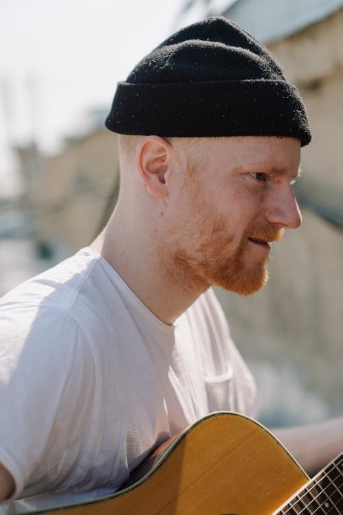 穿着白色圆领t恤和黑色针织帽的男人抱着棕色的原声吉他 · 免费素材图片