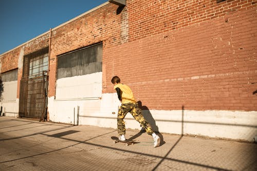 黄色的衬衫和黑色的裤子，在人行道上行走的人 · 免费素材图片