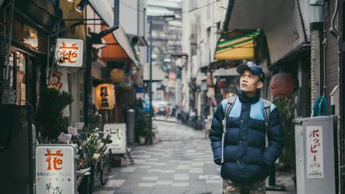 在建筑物包围的灰色混凝土胡同上行走的人 · 免费素材图片