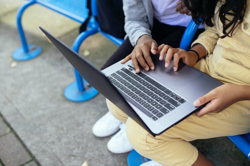 作物多族裔学童在镇上的笔记本电脑上浏览互联网 · 免费素材图片