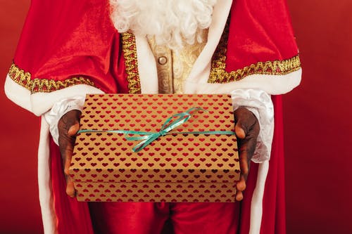 拿着圣诞节礼物的时候穿圣诞老人衣服的人 · 免费素材图片