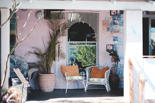 阳光明媚的门廊，配有舒适的椅子和盆栽植物 · 免费素材图片
