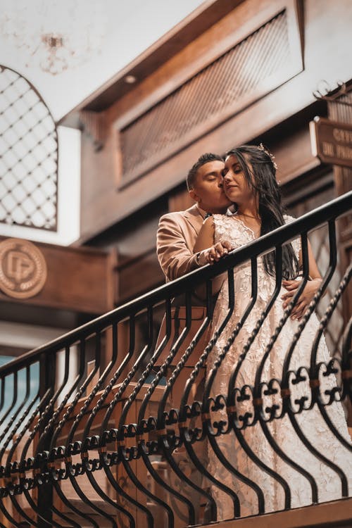 站在黑色金属栅栏旁边的棕色外套的女人 · 免费素材图片