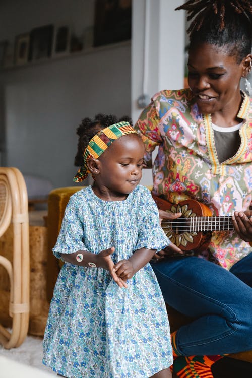 一位母亲一边给女儿唱歌一边弹尤克里里 · 免费素材图片