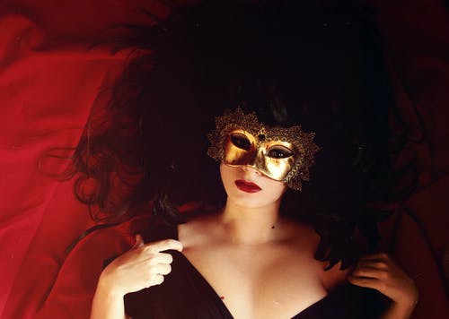 躺在戴着金面具的红色纺织上的女人 · 免费素材图片