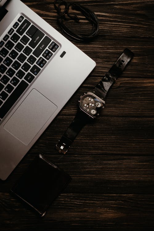 Macbook Pro旁边的银色和黑色圆形模拟手表 · 免费素材图片