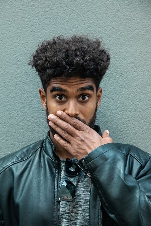 绿色皮夹克遮住他的嘴的男人 · 免费素材图片